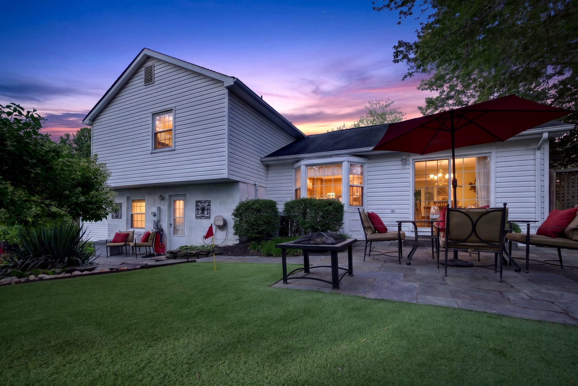 Twilight photo of a backyard with putting green and firepit patio