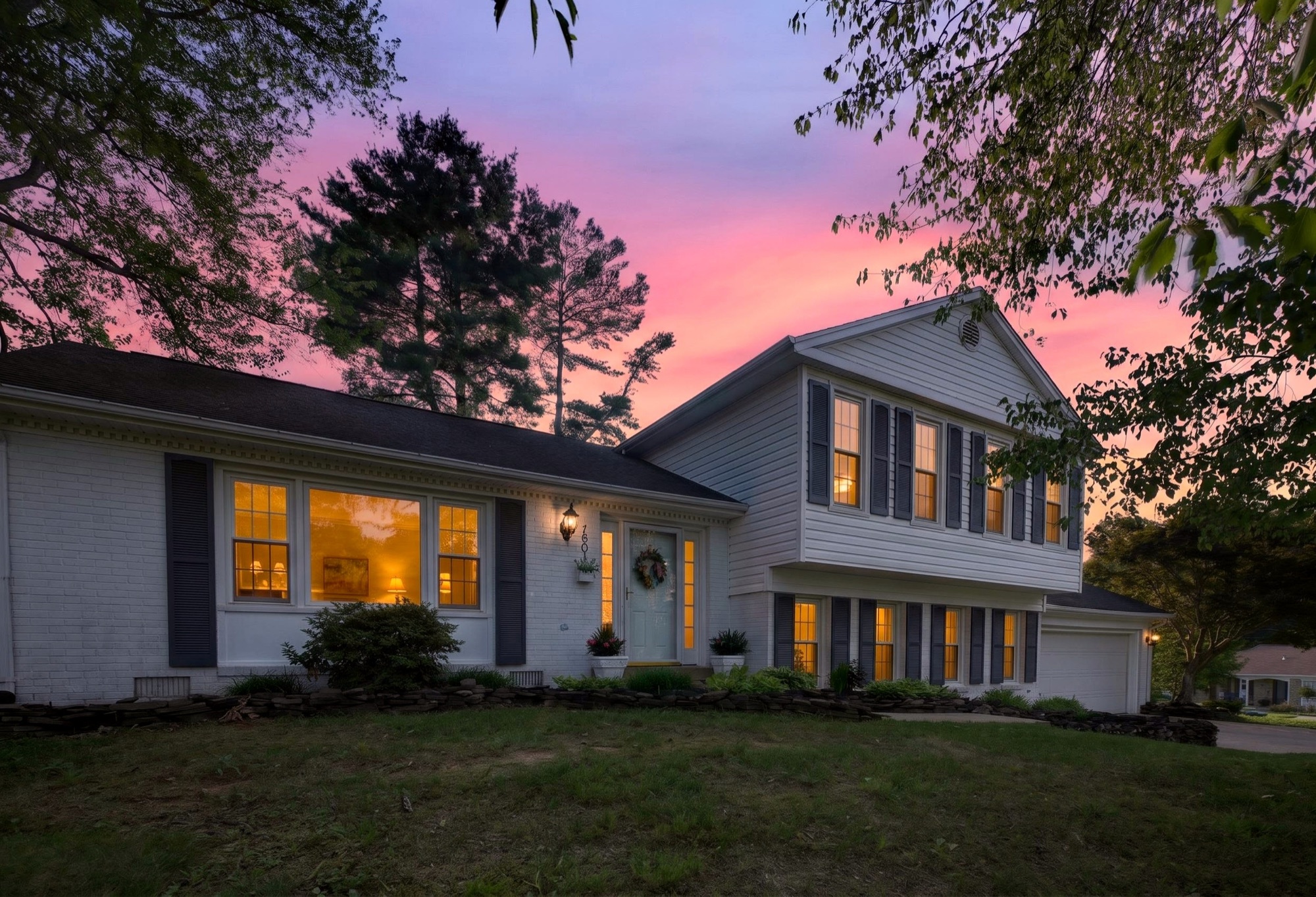 Twilight exterior of a split-level home under a pink sky